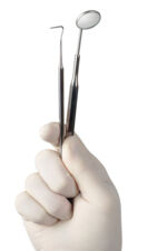 Hand mit dental Instrumenten - zahnärztliche Untersuchung