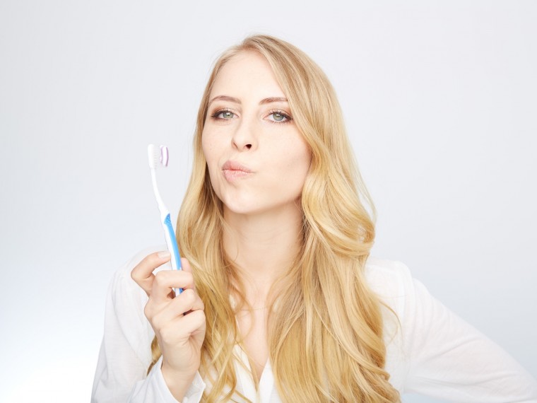 Zahnpflege - Frau mit Zahnbürste fragend