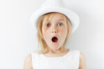 Portrait of emotional beautiful blonde little girl wearing trendy white clothes. Adorable surprised preschool child looking at the camera in astonishment with mouth wide open. shocked with something